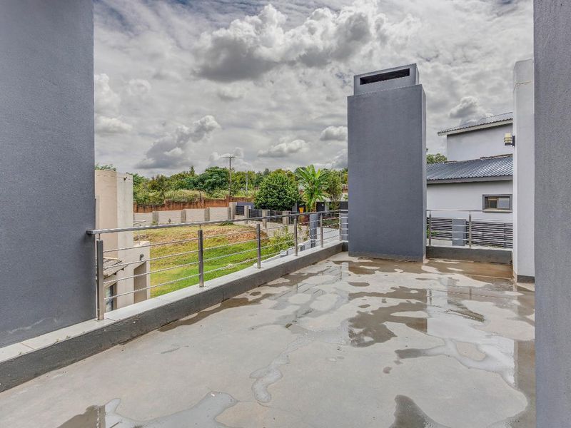 Spacious outdoor balcony featuring a modern stainless steel balustrade and a prominent built-in fireplace chimney, offering an open area for outdoor living.