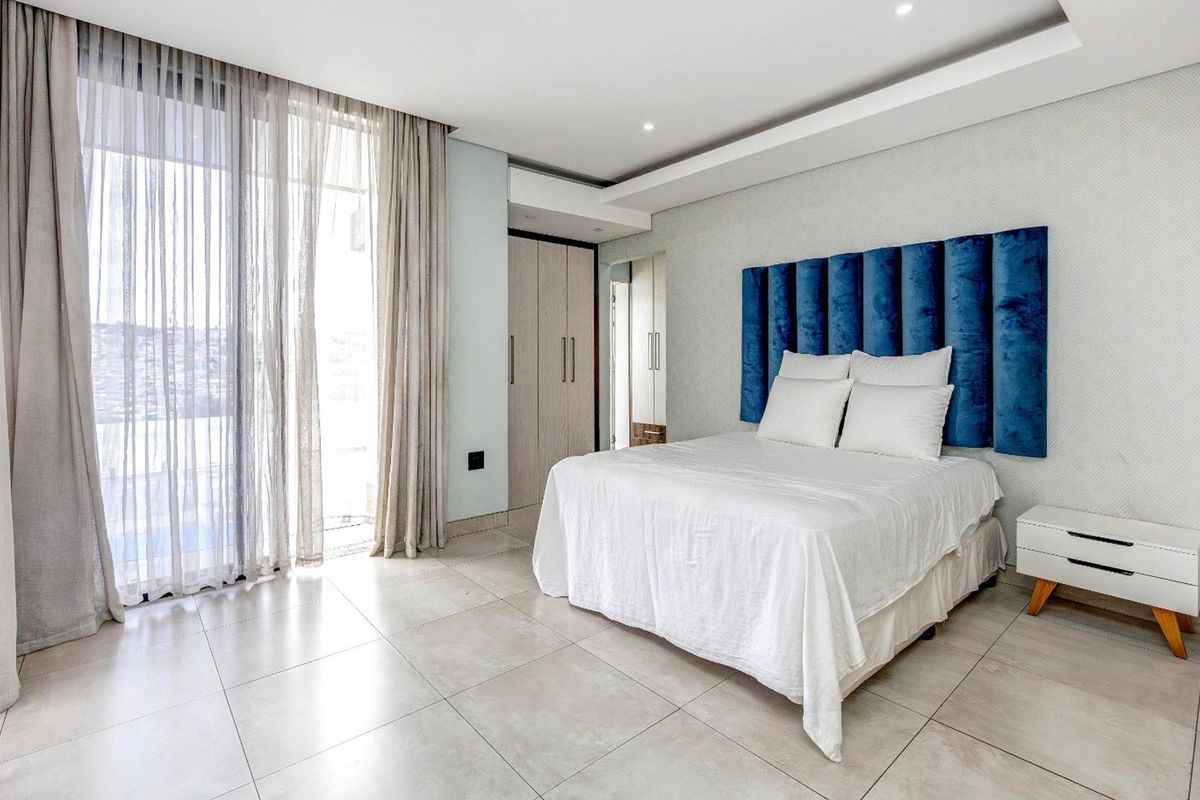 Modern bedroom featuring large format floor tiles, built-in cupboards, and floor-to-ceiling sliding glass doors leading to an outdoor area.