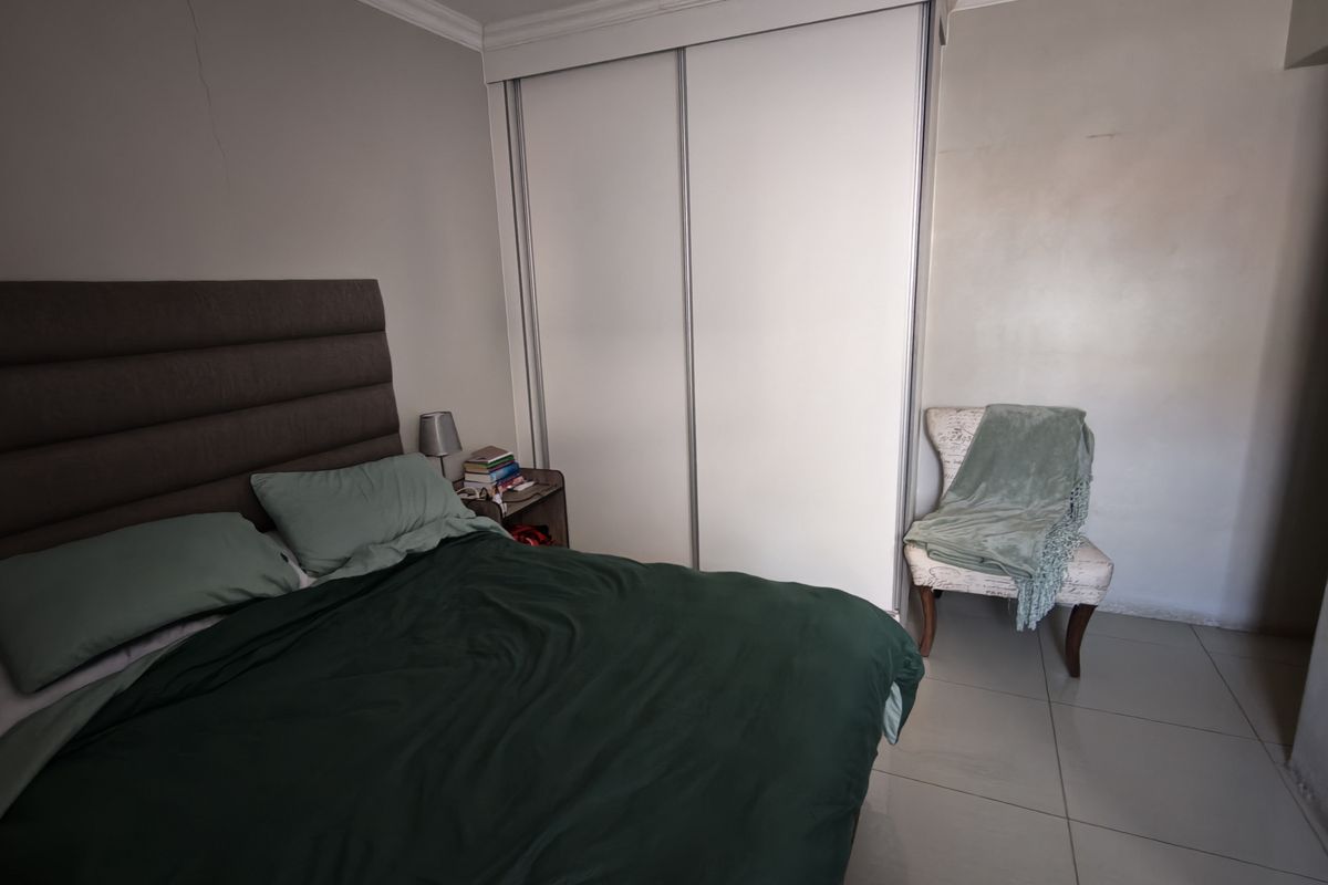 A bedroom featuring tiled flooring, crown molding, and a built-in sliding door wardrobe. A visible wall crack is present.
