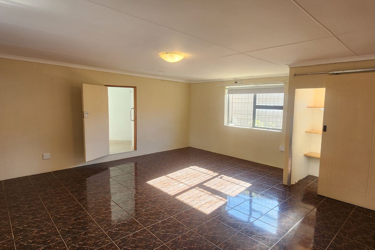 An empty bedroom featuring dark tiled flooring, built-in shelving, and a sliding door, offering a blank canvas for personalization.