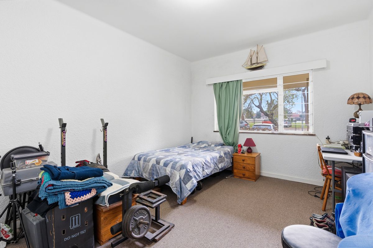 A standard bedroom featuring carpeted flooring and a large window providing natural light.