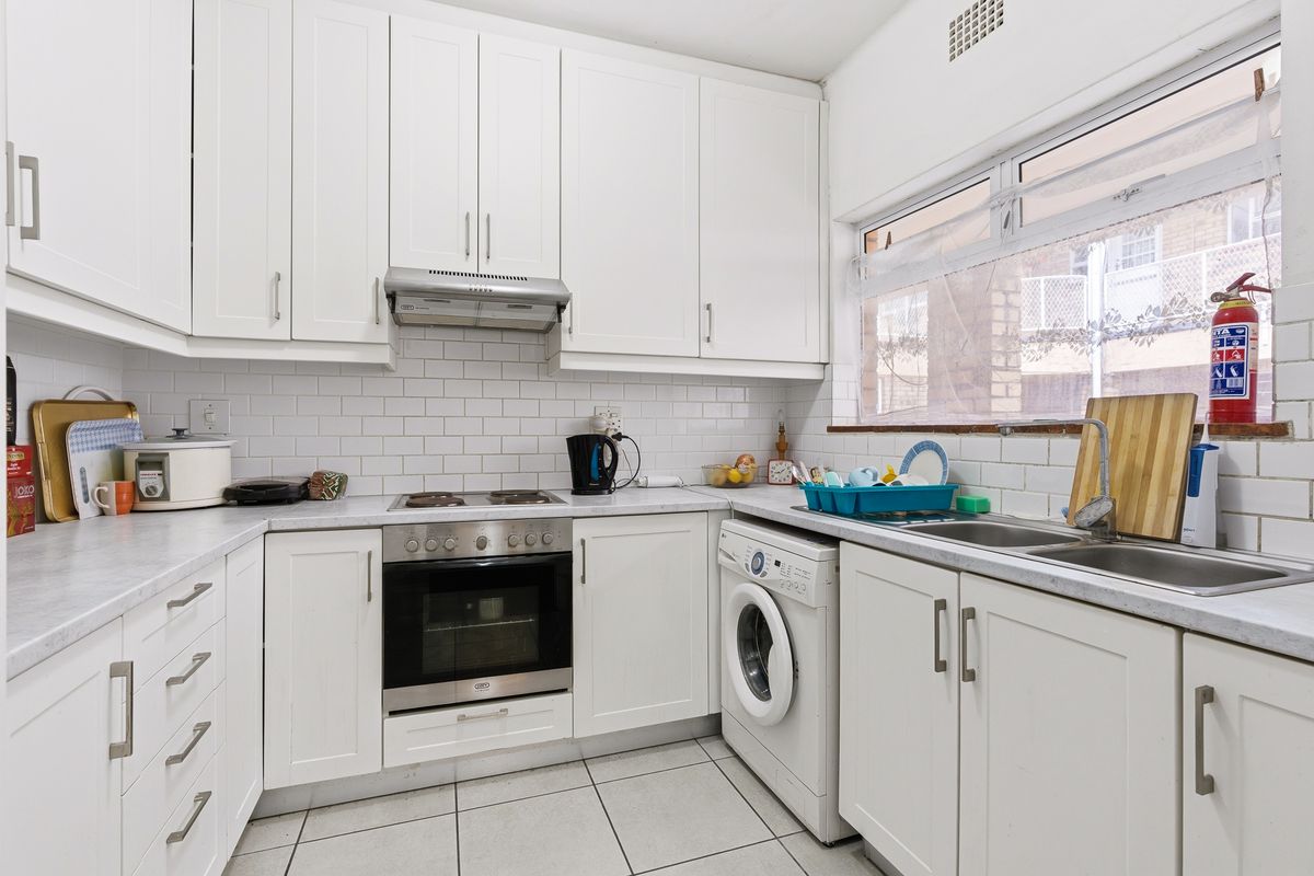 A functional kitchen featuring white cabinetry, subway tile backsplash, built-in oven, electric hob, and integrated laundry plumbing.