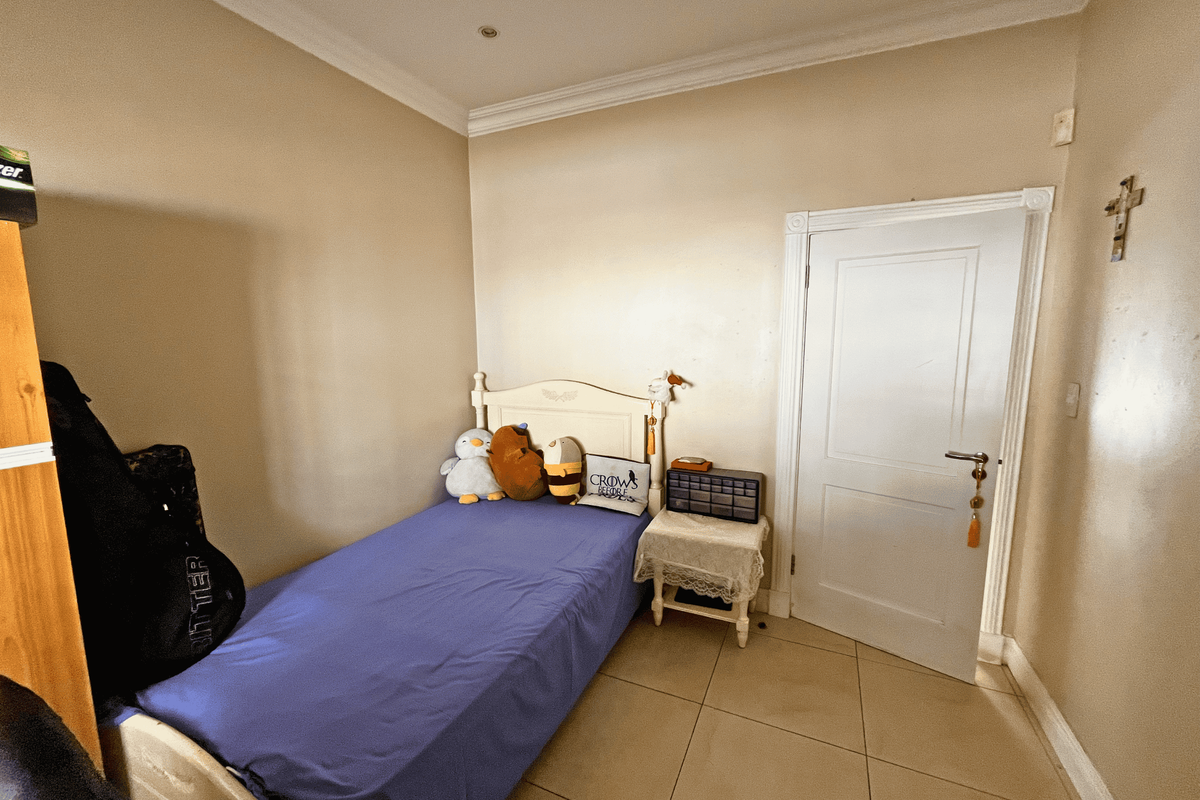 A compact bedroom featuring tiled flooring, coved ceilings, and recessed lighting, offering a functional space ready for personalization.