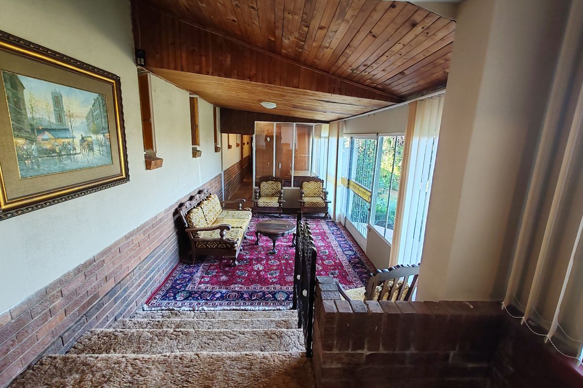 A spacious living area featuring an exposed timber ceiling, brick wall accents, and large sliding glass doors that provide ample natural light.