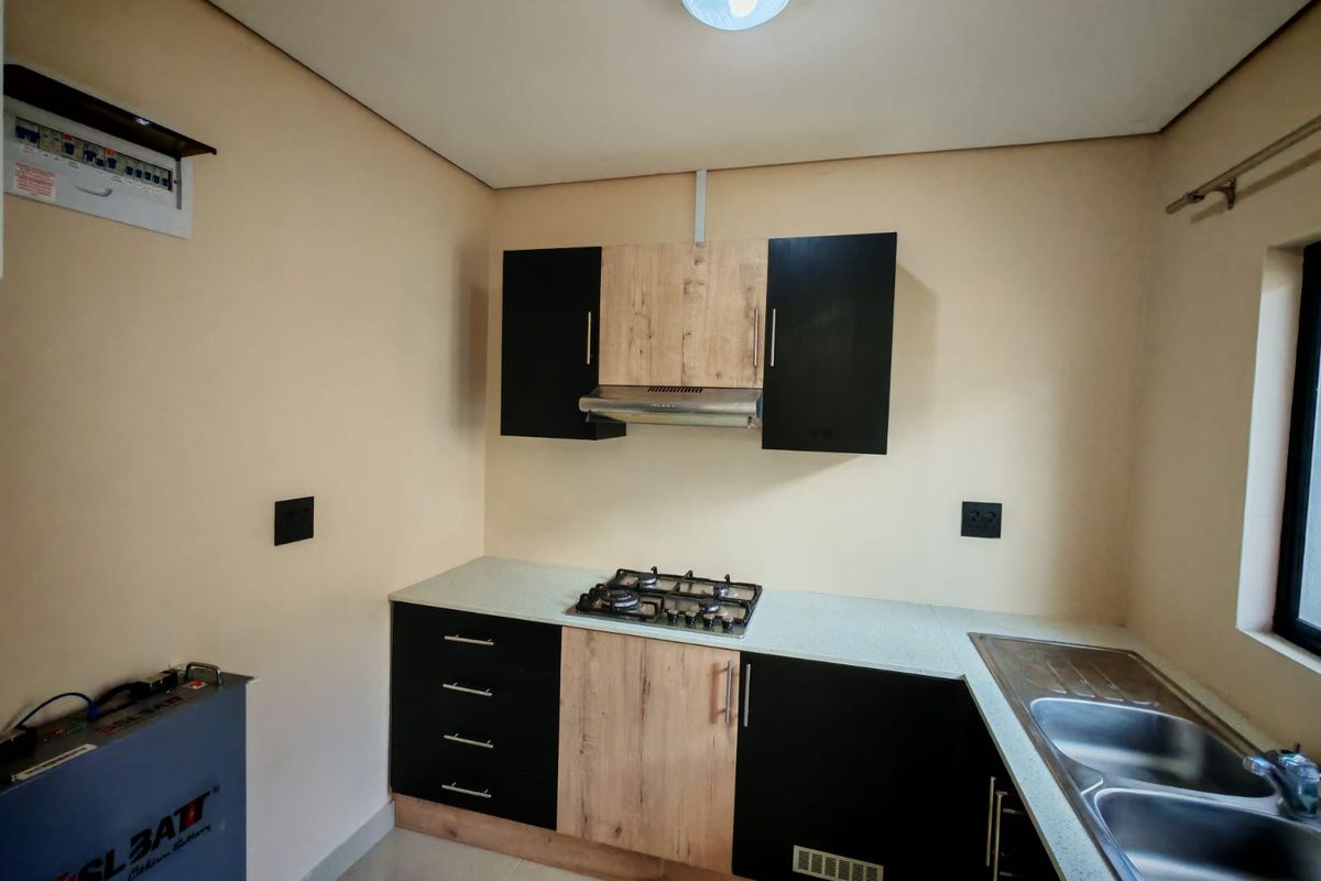 Modern kitchen featuring two-tone cabinetry, a built-in gas hob with extractor fan, and a double stainless steel sink.