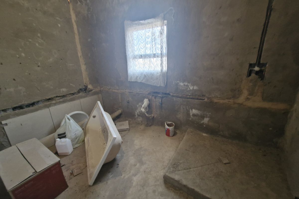 An unfinished bathroom space in shell condition, featuring exposed plumbing and electrical conduits, ready for renovation and custom finishing.