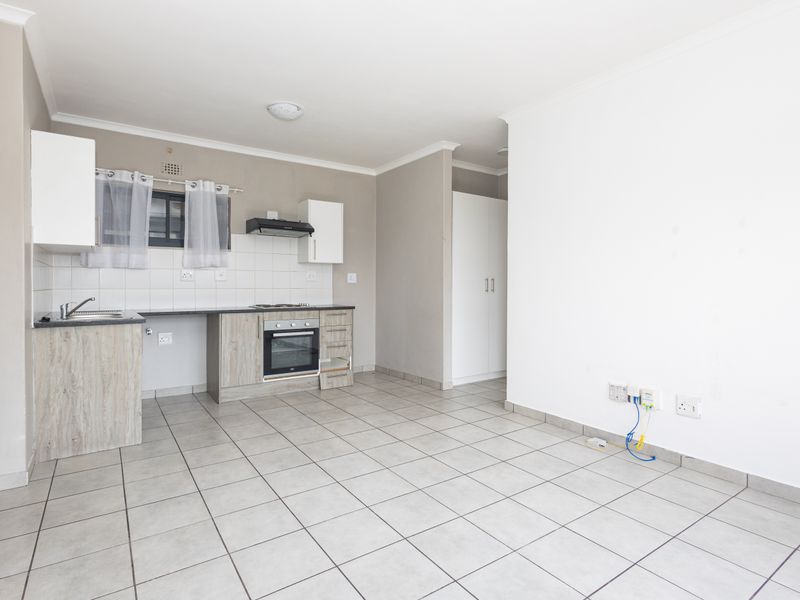 An open-plan kitchen and living area featuring tiled floors, built-in cabinetry, and integrated appliances, offering a functional and versatile living space.