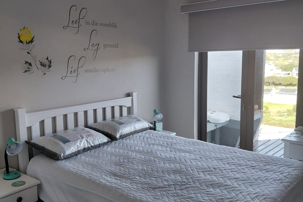 A well-maintained bedroom featuring neutral wall tones, tiled flooring, and a sliding glass door providing access to an outdoor balcony area.