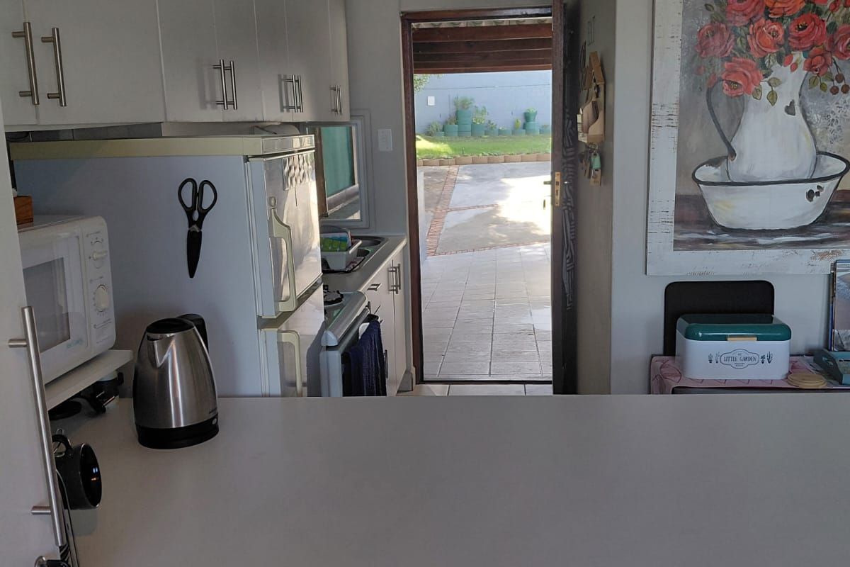 A functional kitchen featuring white cabinetry, a breakfast counter, and direct access to an outdoor patio area.