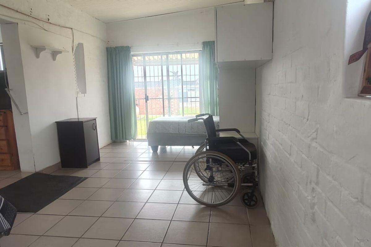 A living area featuring tiled flooring and painted brick walls, with a sliding glass door providing access to the exterior.
