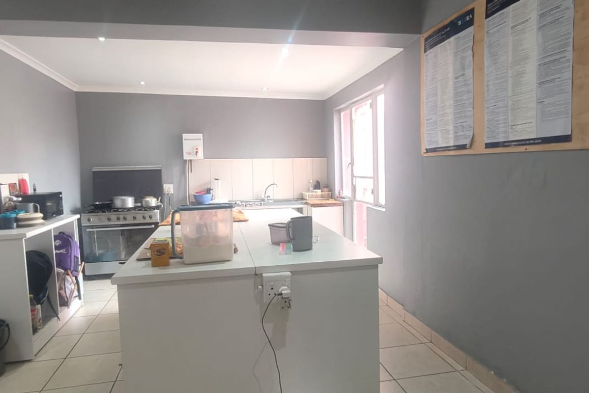 A functional kitchen featuring a central island, tiled flooring, and a freestanding stove, offering a practical layout for daily meal preparation.