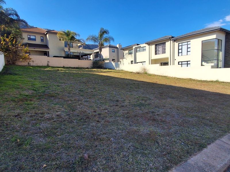 A vacant residential plot situated in a developed neighborhood, featuring established boundary walls and clear access from the street.