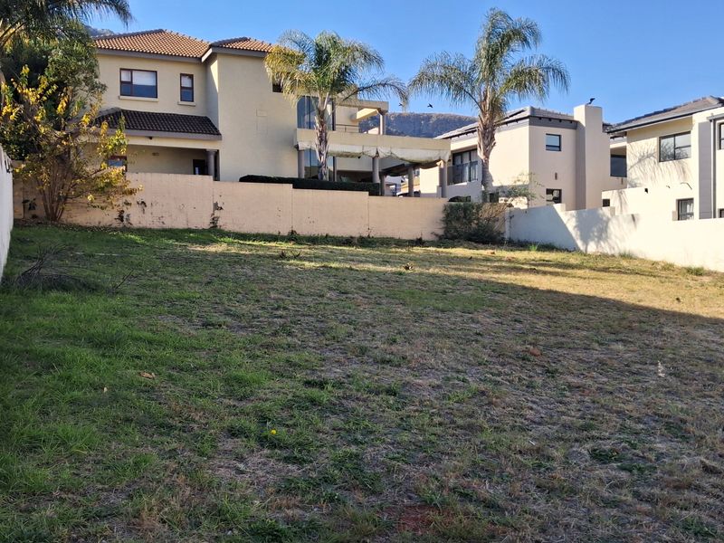 A vacant residential plot featuring a grassed area enclosed by boundary walls, situated in a developed neighborhood setting.