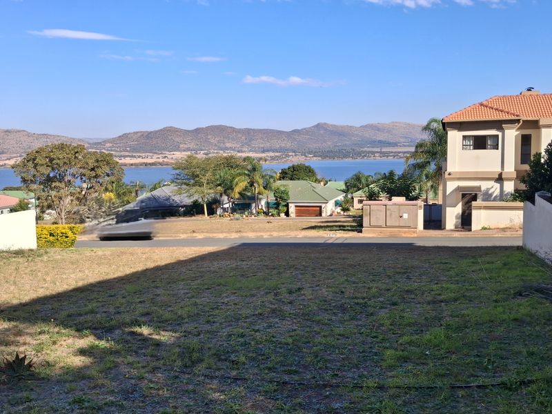 A vacant residential plot offering scenic views of the surrounding landscape, lake, and distant mountains.
