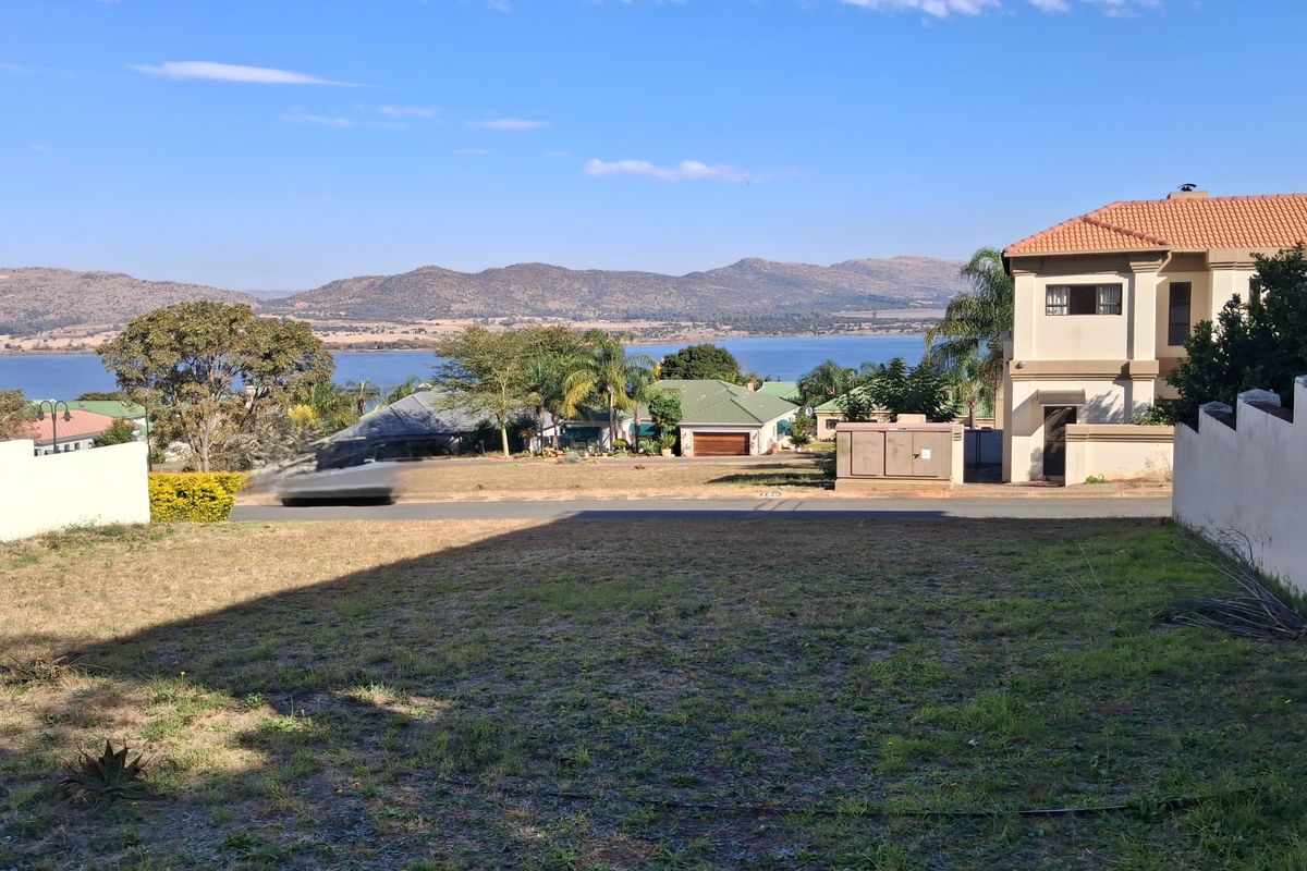 A vacant residential plot offering scenic views of the surrounding landscape, lake, and distant mountains.