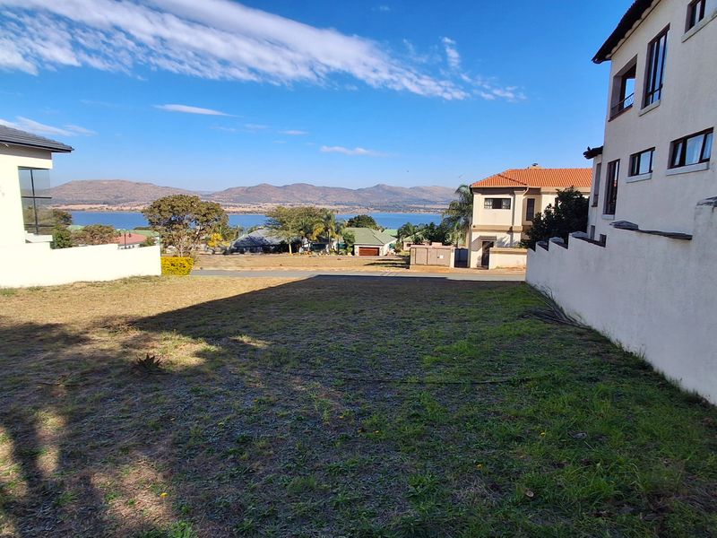 A vacant residential plot situated between existing homes, offering scenic views of the surrounding landscape and distant mountains.