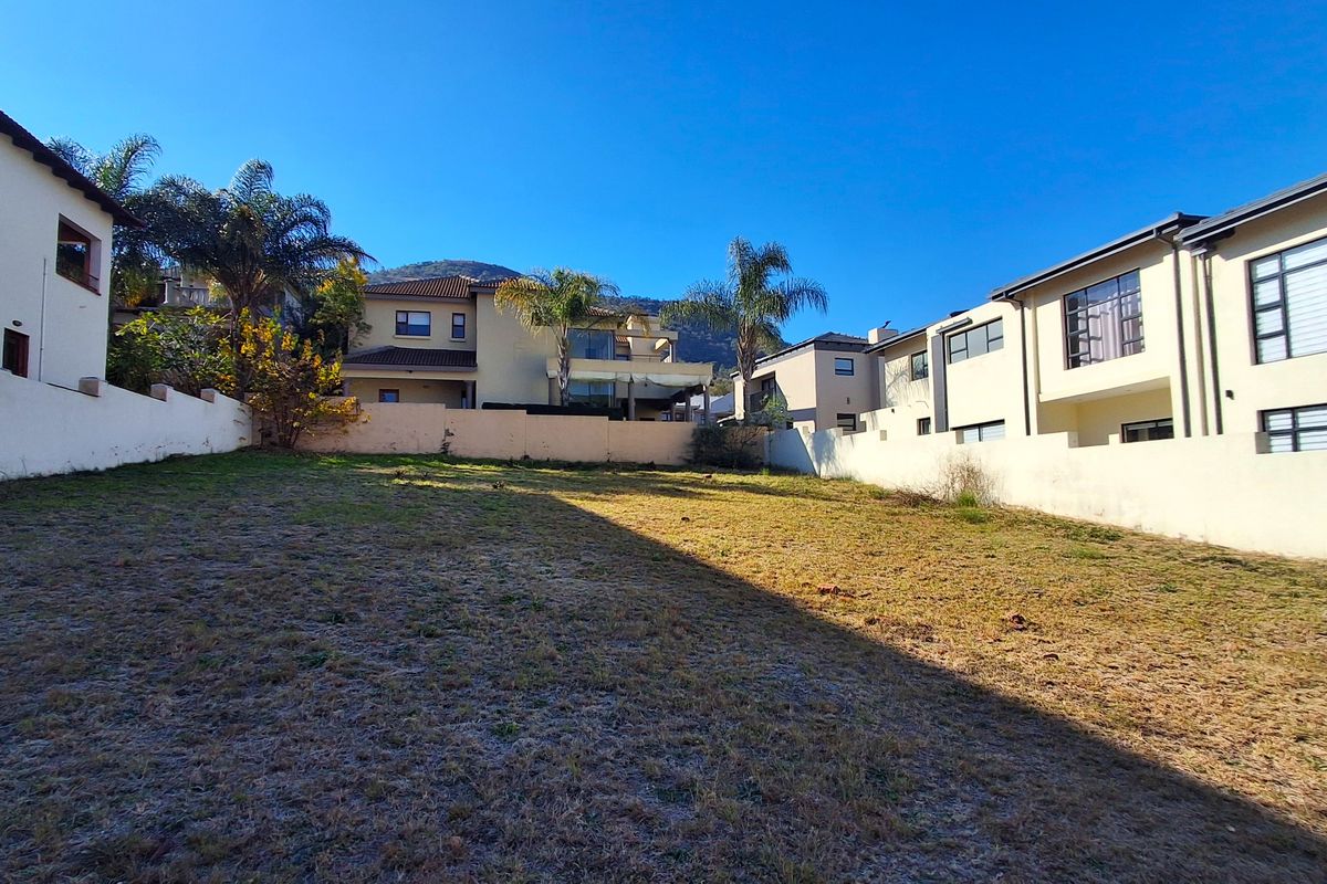 A vacant residential plot enclosed by boundary walls, situated in a developed neighborhood with surrounding multi-story residential properties.