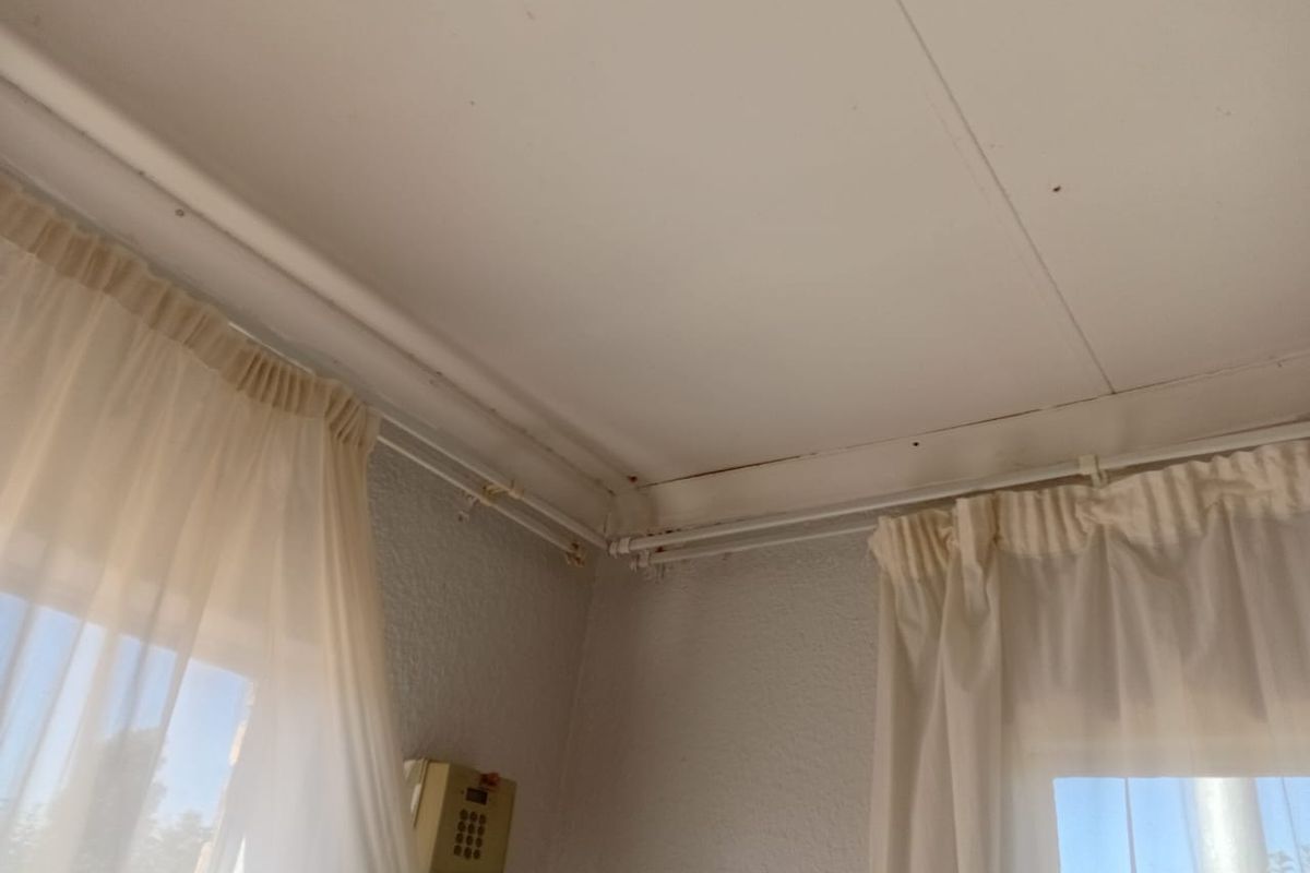 A corner view of a room featuring ceiling panel separation and visible water staining, indicating potential maintenance requirements for the ceiling structure.