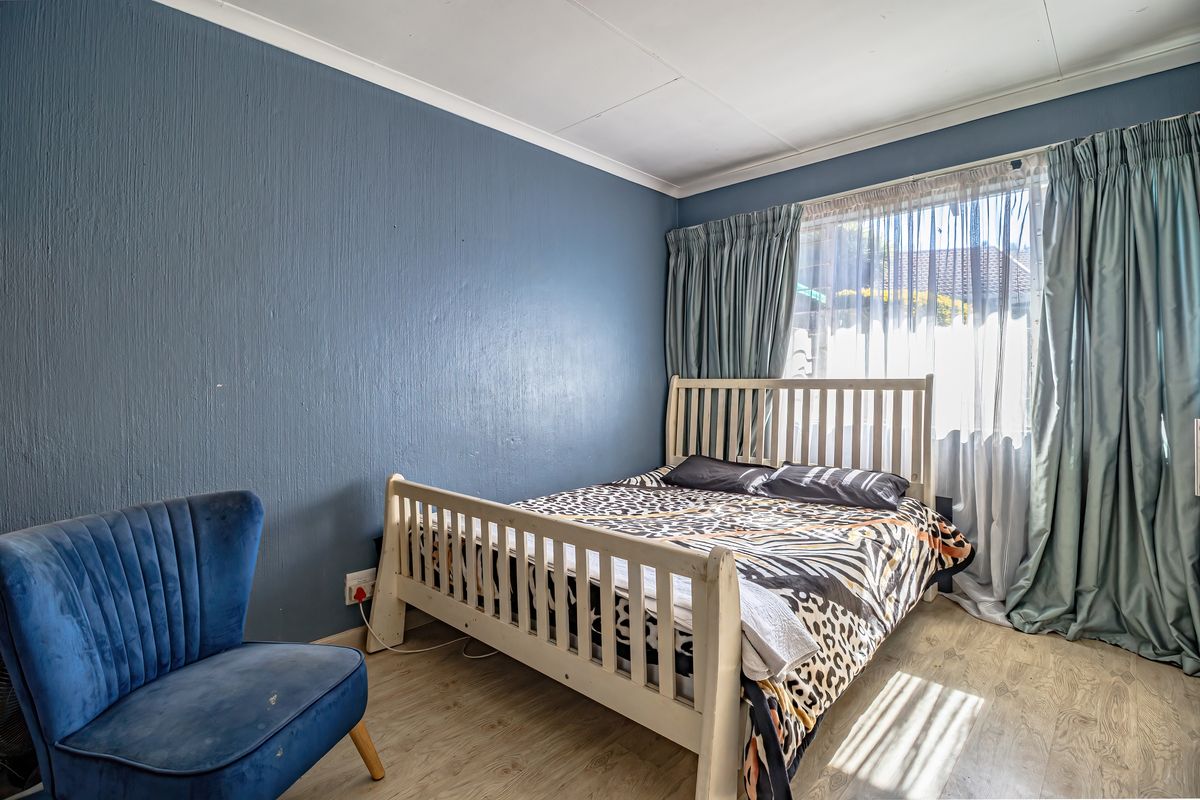A bedroom featuring laminate flooring and a large window with curtain tracks, providing natural light and a functional living space.