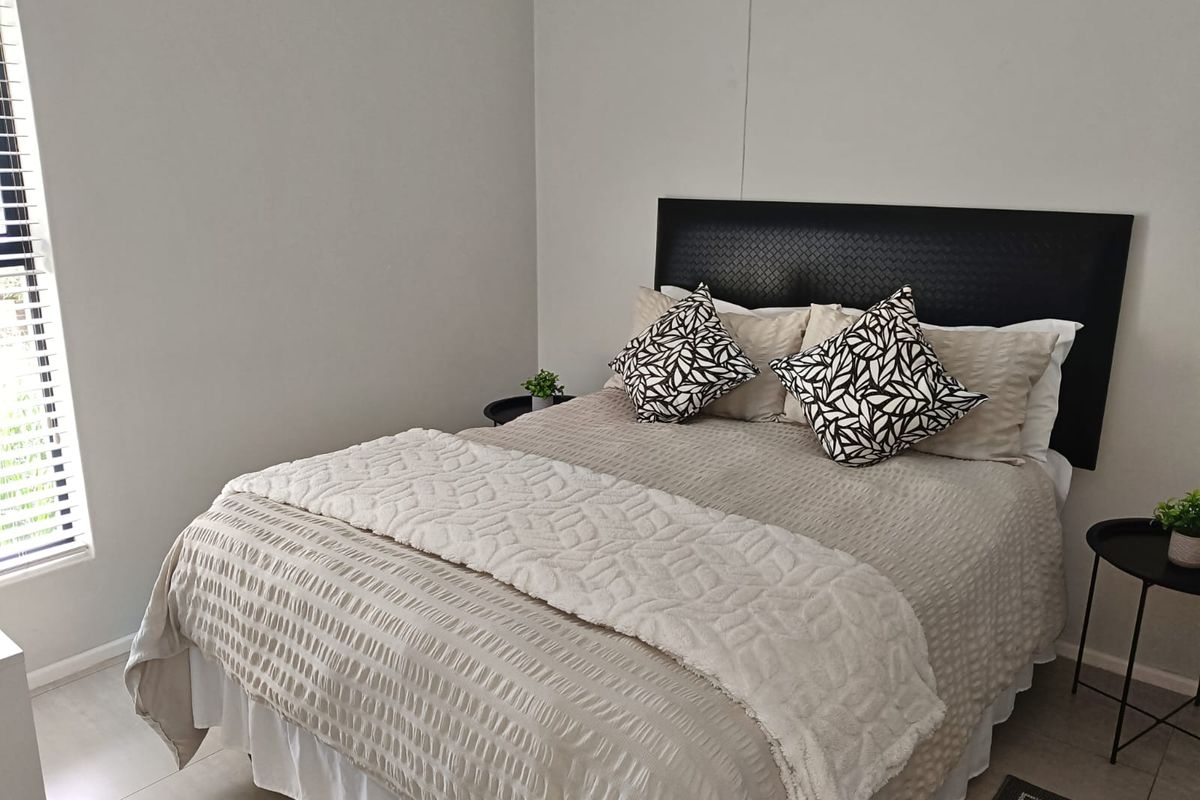 A well-maintained bedroom featuring neutral tiled flooring and venetian blinds, providing a clean and comfortable living space.