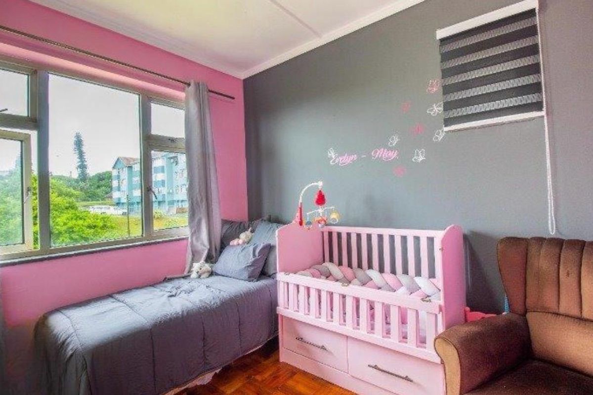 A bedroom featuring parquet flooring, aluminium window frames, and a roller blind, currently styled as a nursery.