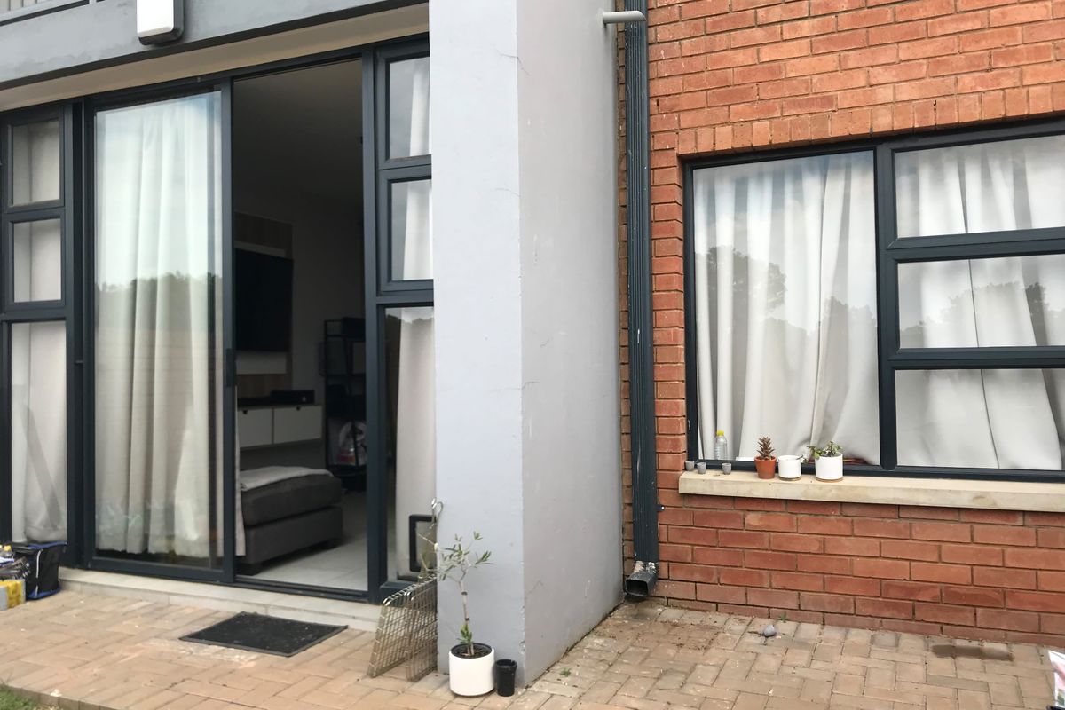 Exterior view of an apartment patio featuring brick facade, sliding glass doors, and paved outdoor area.