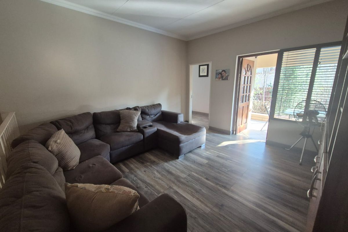A living room featuring laminate flooring and direct access to an outdoor patio area through a sliding door.