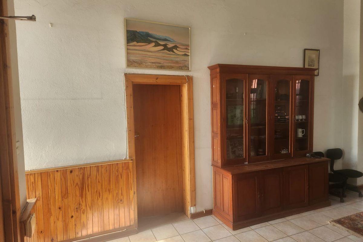 A living area featuring tiled flooring and timber wall paneling, providing a dated aesthetic that could be updated with modern finishes.
