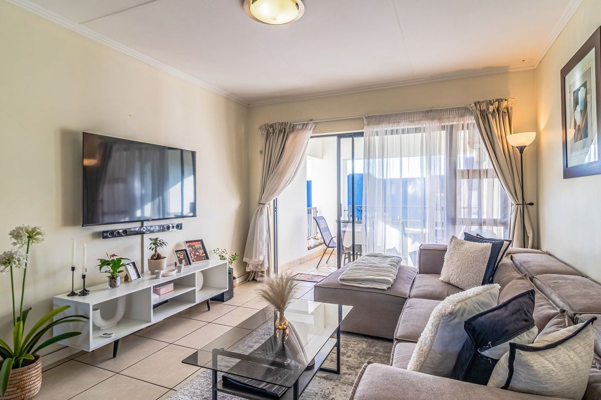A bright living room featuring tiled flooring and a large sliding glass door that provides access to an outdoor patio area.