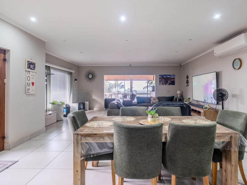 Spacious open-plan living and dining area featuring tiled floors, recessed lighting, and direct access to an outdoor patio through sliding glass doors.
