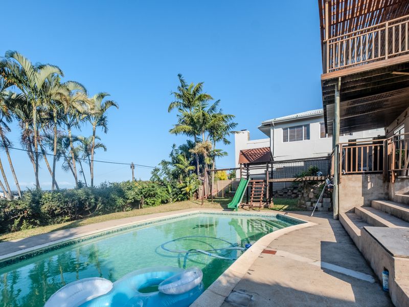 Outdoor pool area featuring a swimming pool, concrete decking, and a raised timber balcony structure overlooking the garden.