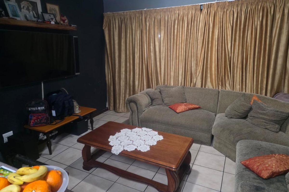 A living room featuring tiled flooring and dark accent walls, providing a functional space for relaxation.