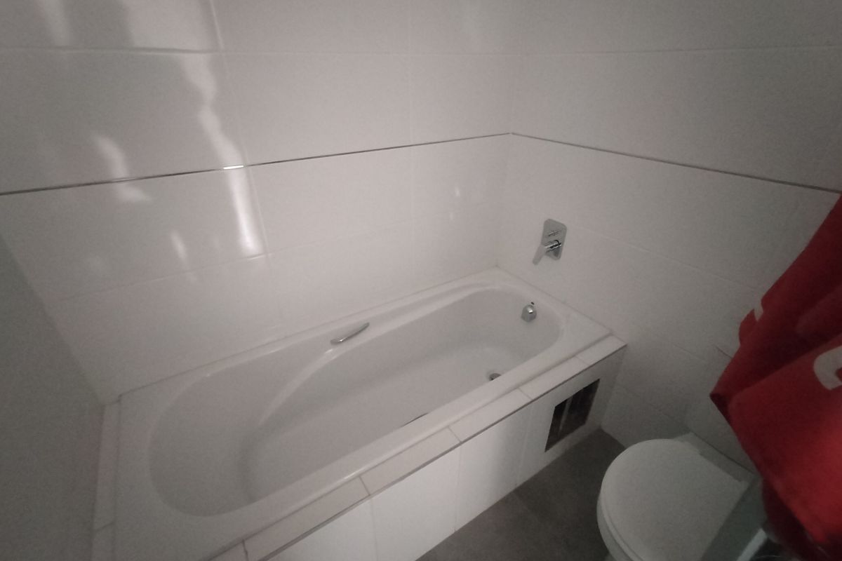 A functional bathroom featuring a built-in bathtub with wall-mounted fixtures and tiled wall finishes.