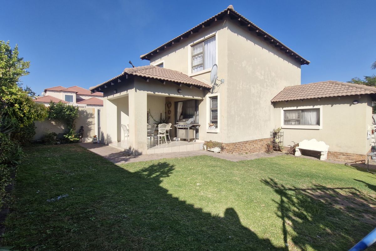 Rear view of the house featuring a covered patio, tiled roof, and a well-maintained lawn area.