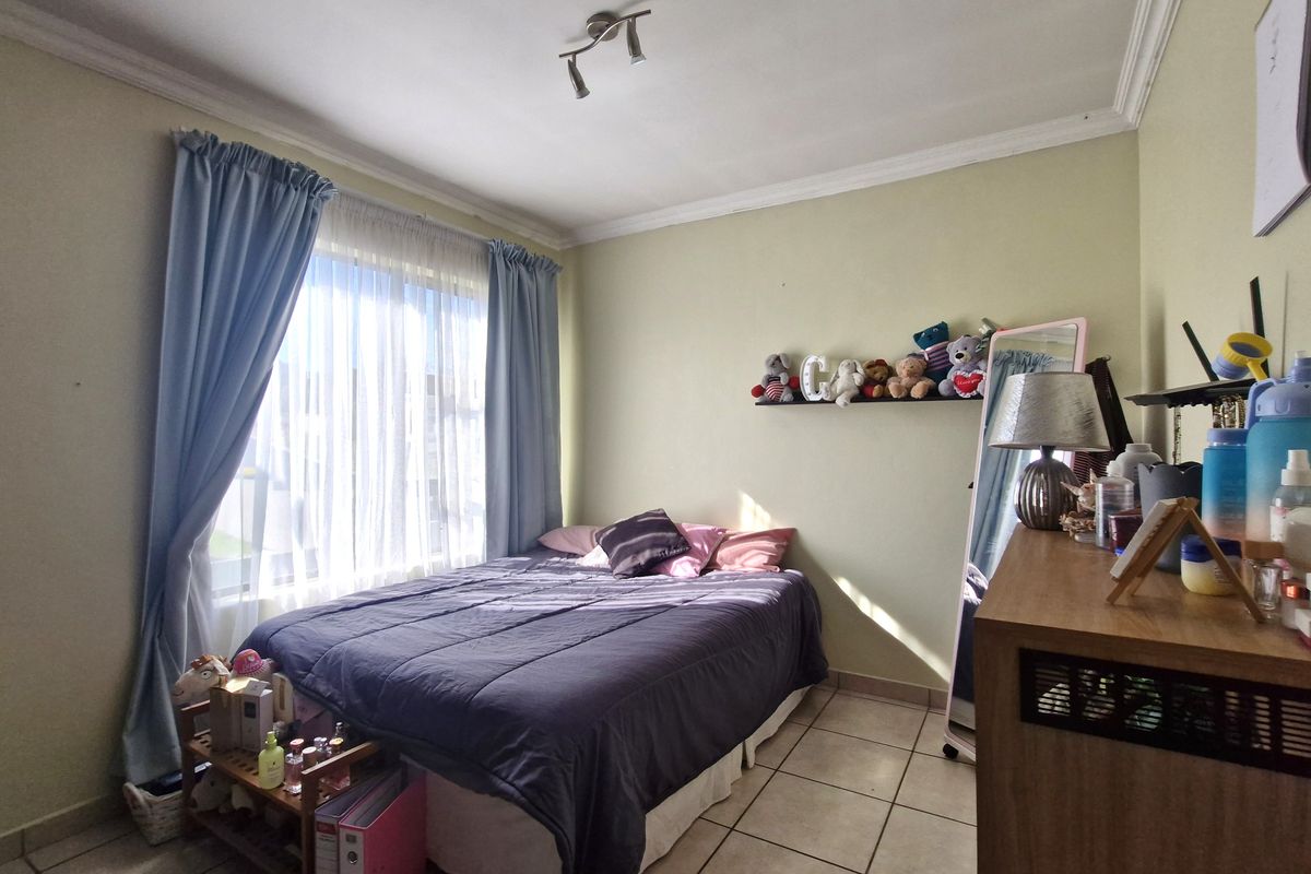 A functional bedroom featuring tiled flooring, ceiling coving, and large windows with curtain rails, providing a neutral base for personalization.