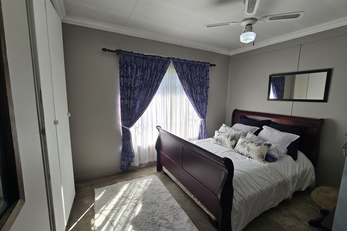A well-lit bedroom featuring built-in cupboards, a ceiling fan, and neutral wall finishes, providing a comfortable and functional sleeping space.