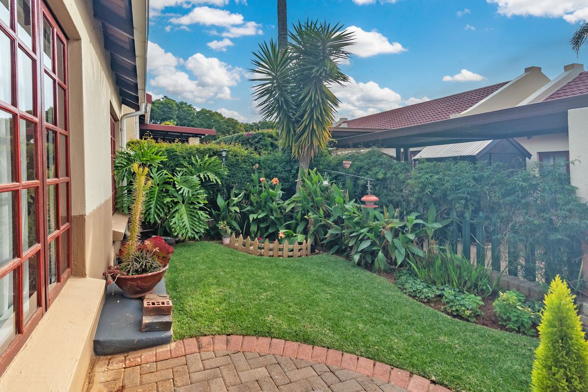 A well-maintained rear garden featuring a paved patio area, lush lawn, and established perimeter landscaping, providing a private outdoor space.