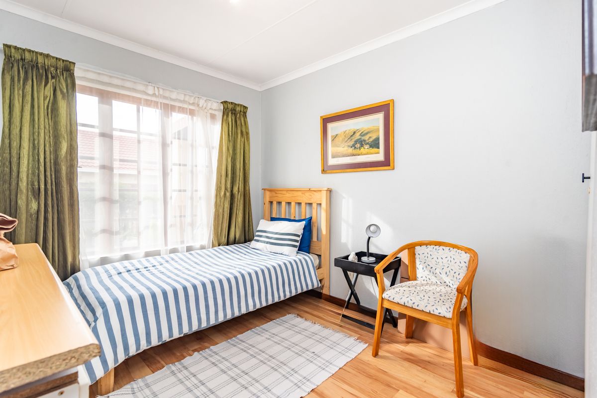 A well-lit bedroom featuring laminate flooring and coved ceilings, offering a functional and comfortable living space.
