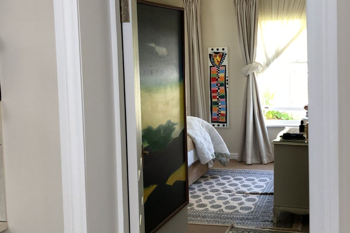 A view through a doorway into a bedroom featuring carpeted flooring, neutral wall tones, and window treatments.