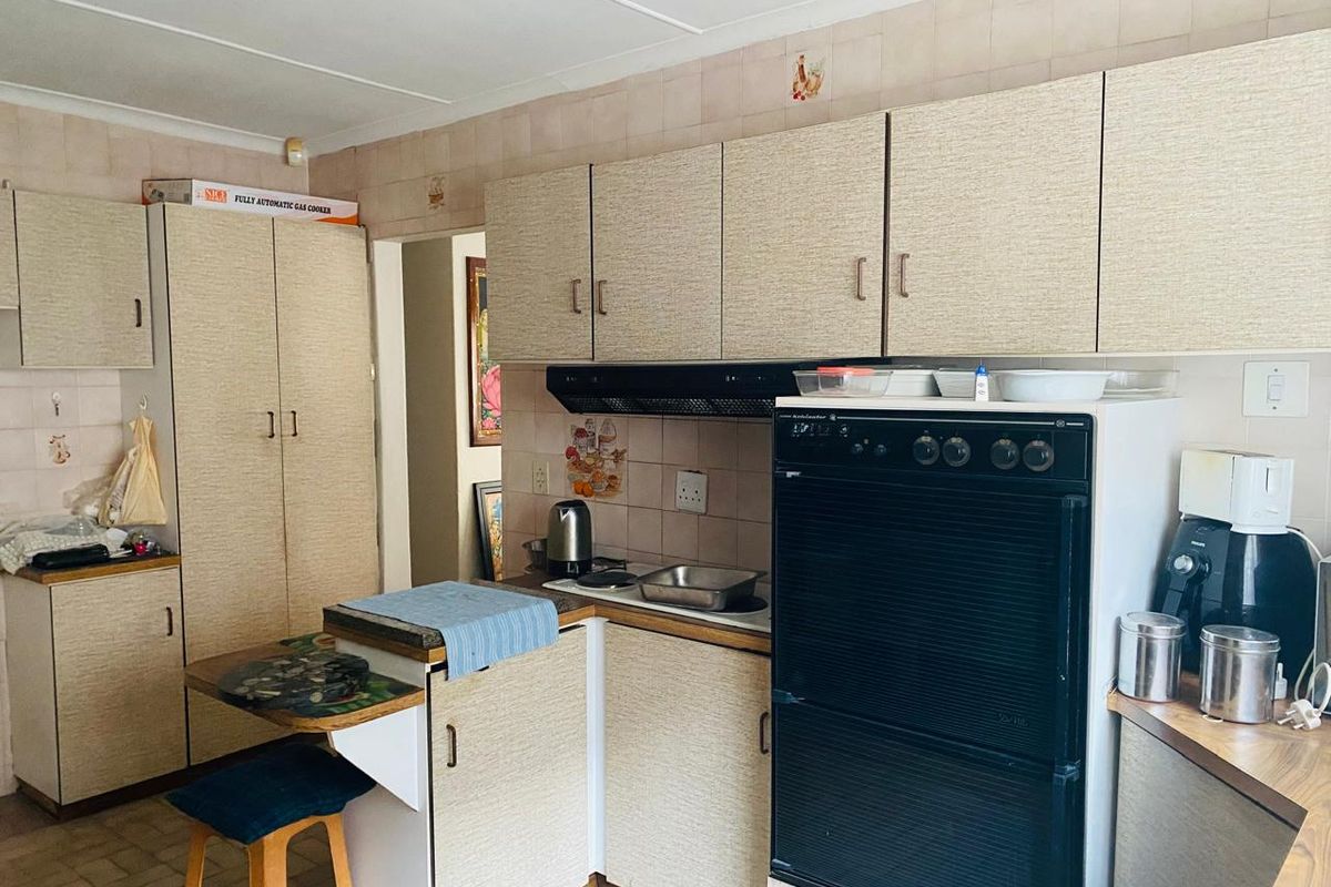 A dated kitchen featuring laminate cabinetry, a built-in oven, an extractor fan, and tiled splashbacks, offering potential for a modern renovation.