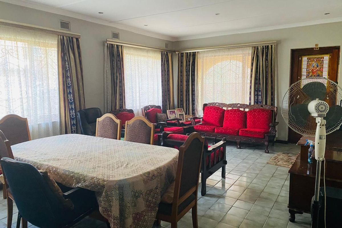 Spacious living and dining area featuring tiled flooring, recessed lighting, and large windows with security gates, offering a functional and well-lit living space.