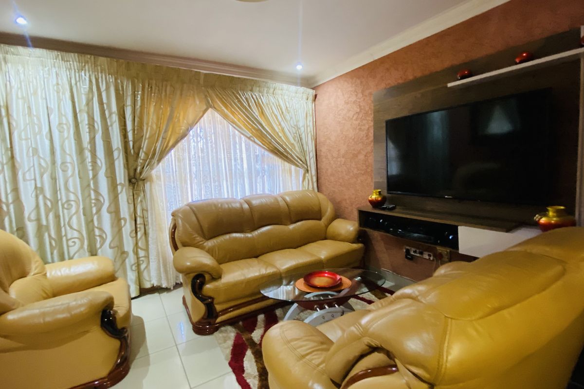 A comfortable living room featuring tiled flooring, recessed downlighting, and a built-in media unit for entertainment.