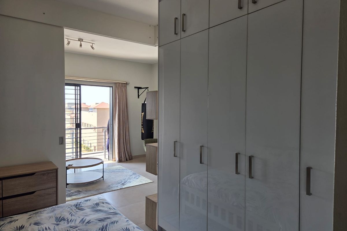 Bedroom featuring extensive built-in cupboards and a sliding door leading to a balcony, providing natural light and access to outdoor space.