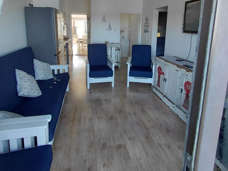 Open-plan living area featuring light wood-look laminate flooring and a connected kitchen space, providing a functional and versatile layout.