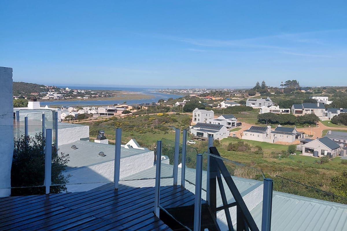 Elevated timber balcony featuring a glass balustrade and metal staircase, offering expansive coastal and landscape views.