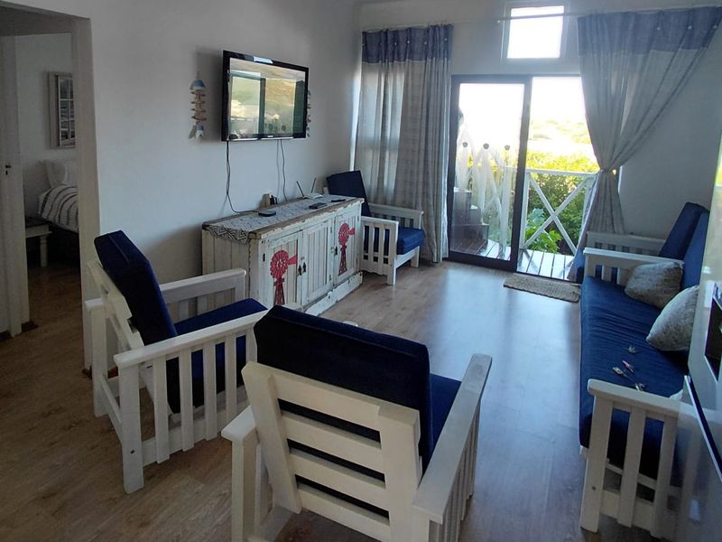 A living room featuring laminate flooring and a sliding glass door providing access to an outdoor balcony area.
