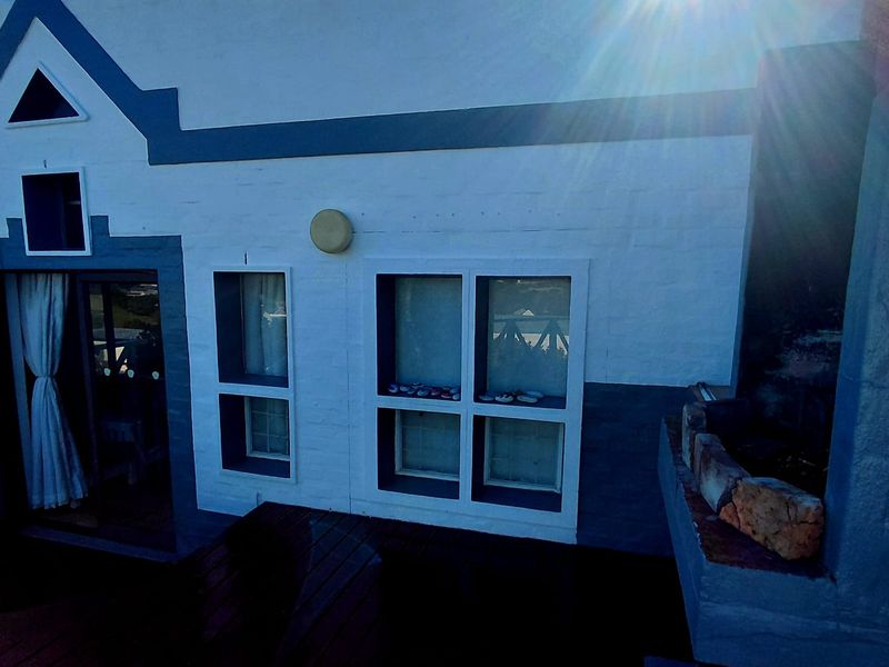 An elevated balcony area featuring wooden decking, a built-in braai, and direct access to the interior through a sliding glass door.