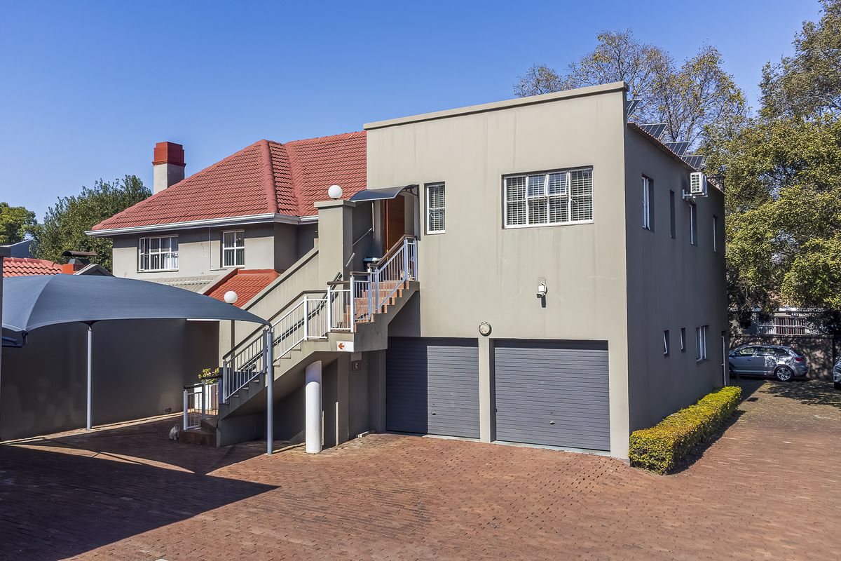 Rear view of the property featuring a double garage, external staircase access, paved driveway, and a shade sail carport.