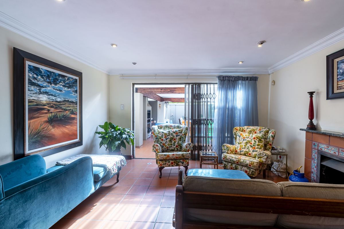 A living room featuring tiled flooring, a fireplace with a decorative tiled surround, and sliding glass doors providing access to an outdoor patio area.