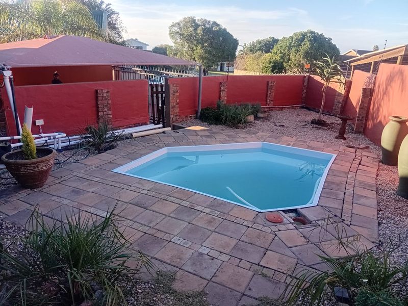 Outdoor pool area featuring a paved deck, perimeter wall, and shade sail, providing a functional space for recreation and relaxation.